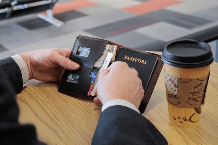 Traveler in Airport With His Passport Wallet Open Looking Through Tickets